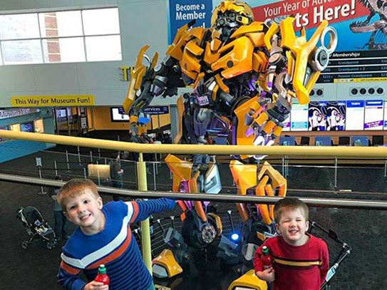 Children posing in front of Bumblebee in the Welcome Center.